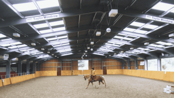 Filon Rooflights Horse a person riding a horse in an indoor arena with natural lighting from Filon rooflights