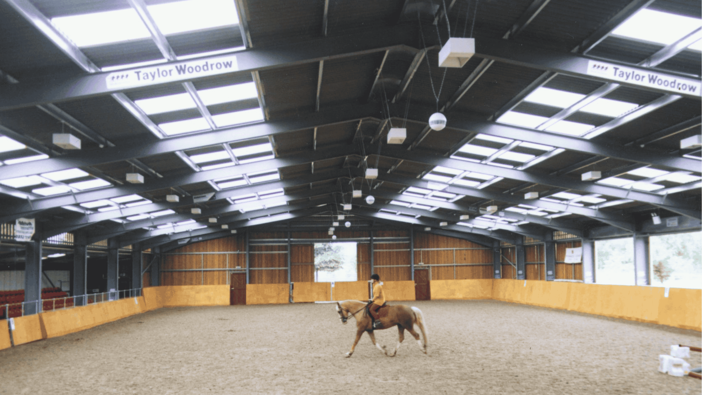 Filon Rooflights Horse a person riding a horse in an indoor arena with natural lighting from Filon rooflights